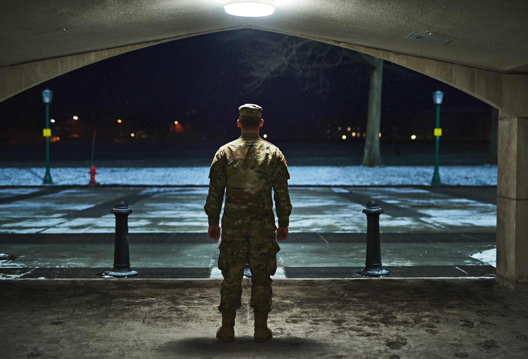 Rearview shot of a young soldier standing outside on a cold night at a military academy