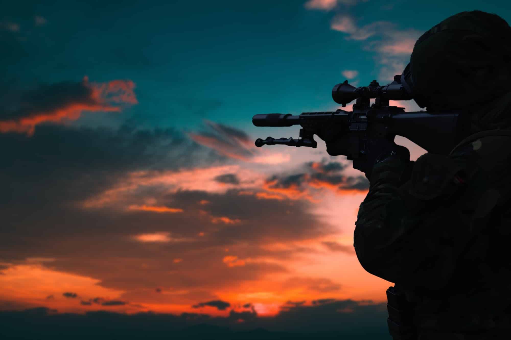 Silhouette of a military soldier with weapons at sunset